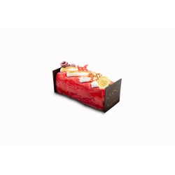 Gâteau allongé rouge, décoré de fruits et chocolat, sur fond blanc élégant.