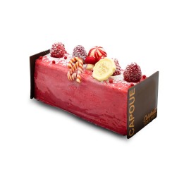 Gâteau rectangulaire aux framboises, décoré de bonbons et fruits frais, sur un fond chocolaté.