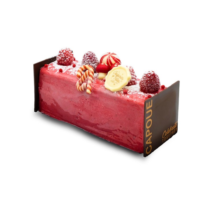 Gâteau rectangulaire aux framboises, décoré de bonbons et fruits frais, sur un fond chocolaté.