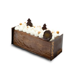Bûche de Noël en chocolat, décorée de crème, arbres en chocolat et billes dorées.