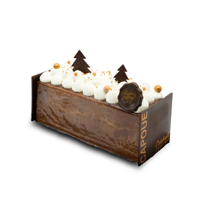 Bûche de Noël en chocolat, décorée de crème, arbres en chocolat et billes dorées.