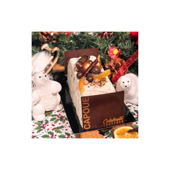 Bûche de Noël décorée de fruits secs et chocolat, entourée d'ours en peluche et de verdure.