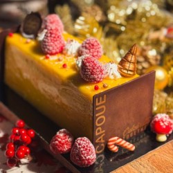 Gâteau rectangulaire aux fruits, décoré de framboises et de bonbons festifs.