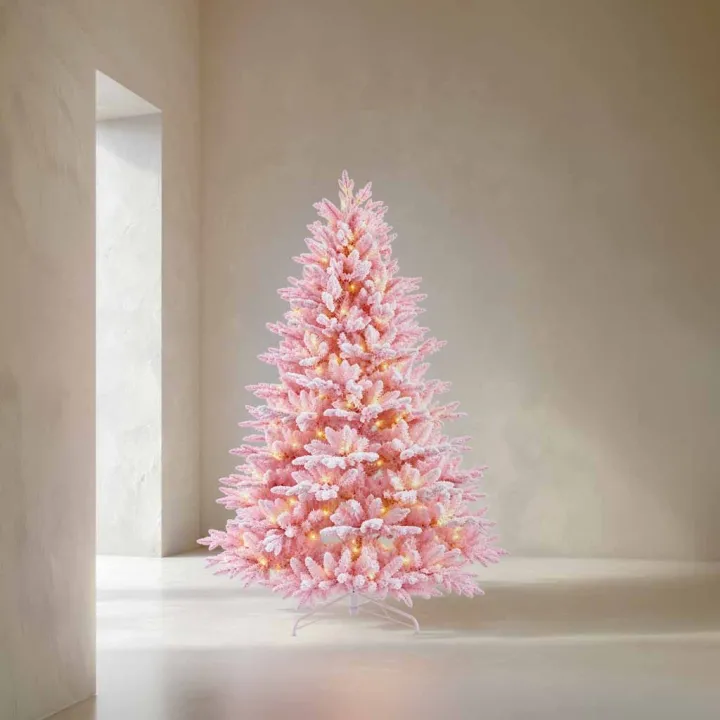 Arbre de Noël rose pastel, décoré de lumière douce, sur fond sobre et élégant.