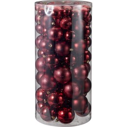 Boules de Noël rouges brillantes et mates, empilées dans un cylindre transparent.