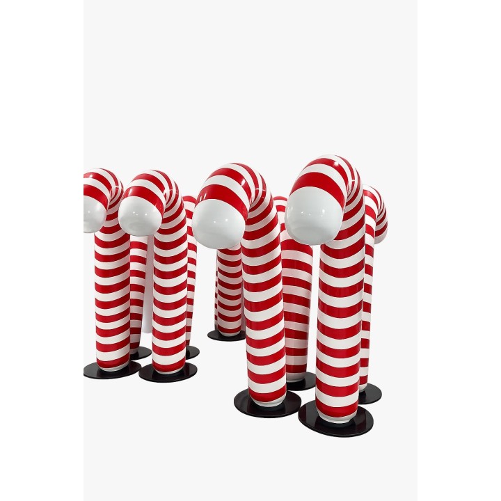 Figures allongées en forme de bras rayés rouges et blancs, sur socles noirs, avec têtes blanches.